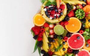 Un assortiment coloré de tranches d'oranges, pamplemousses, citron vert, kiwi, fraises, mûres, framboises, myrtilles, ananas et bananes.
